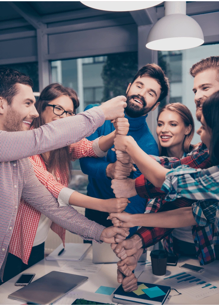 A Joomag team stacking hands together over a desk